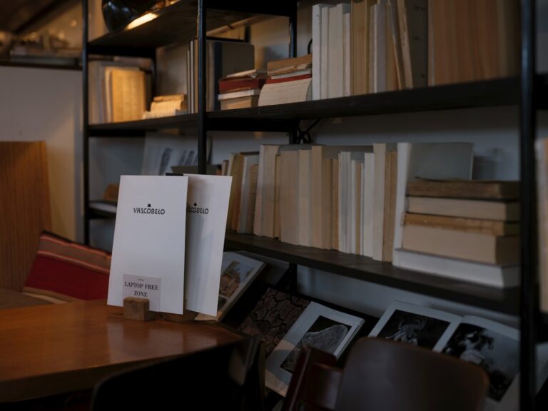 Uma Estante De Livros Cheia De Livros Ao Lado De Uma Mesa De Madeira R1ecJTnE6bM