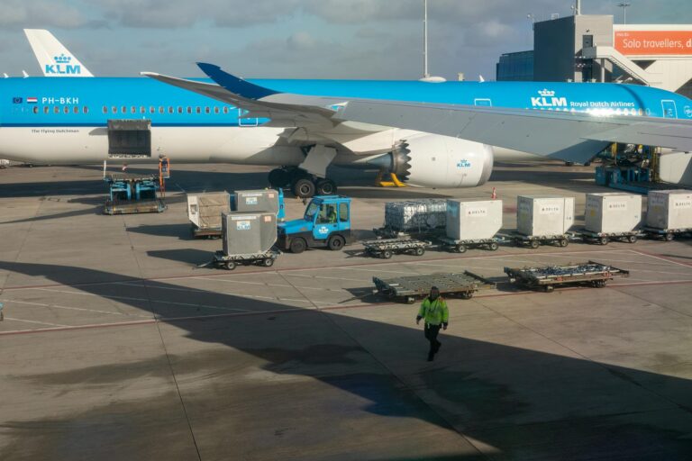 KLM aircraft preparing for departure on a sunny day with ground crew assisting.