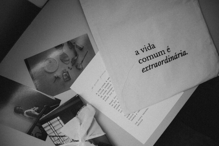 Monochrome still life featuring Portuguese text 'a vida comum é extraordinária' on paper.