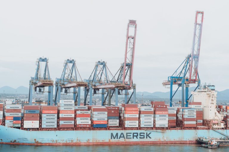 Container ship Maersk loading at a busy industrial port under cranes.